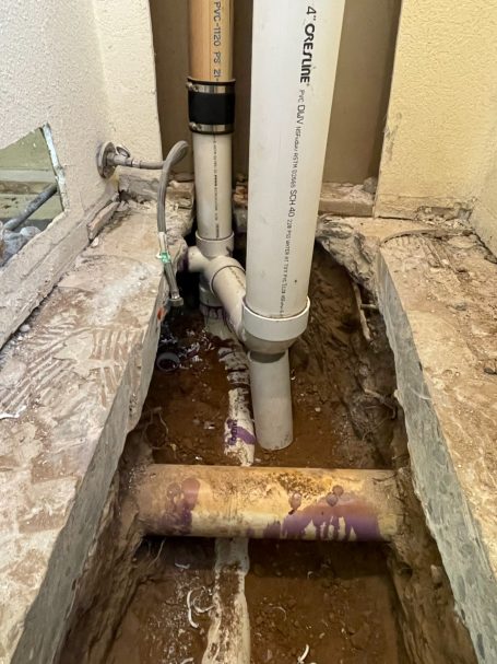 Image of some plumbing that we were working on during a repipe. Exposed plumbing pipes with drainage connections in a concrete floor.