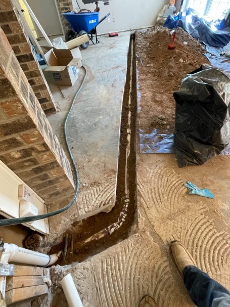 Image from Repipe in San Angelo TX Trench in a construction area with exposed pipe and dirt, showing a sloped drainage path.